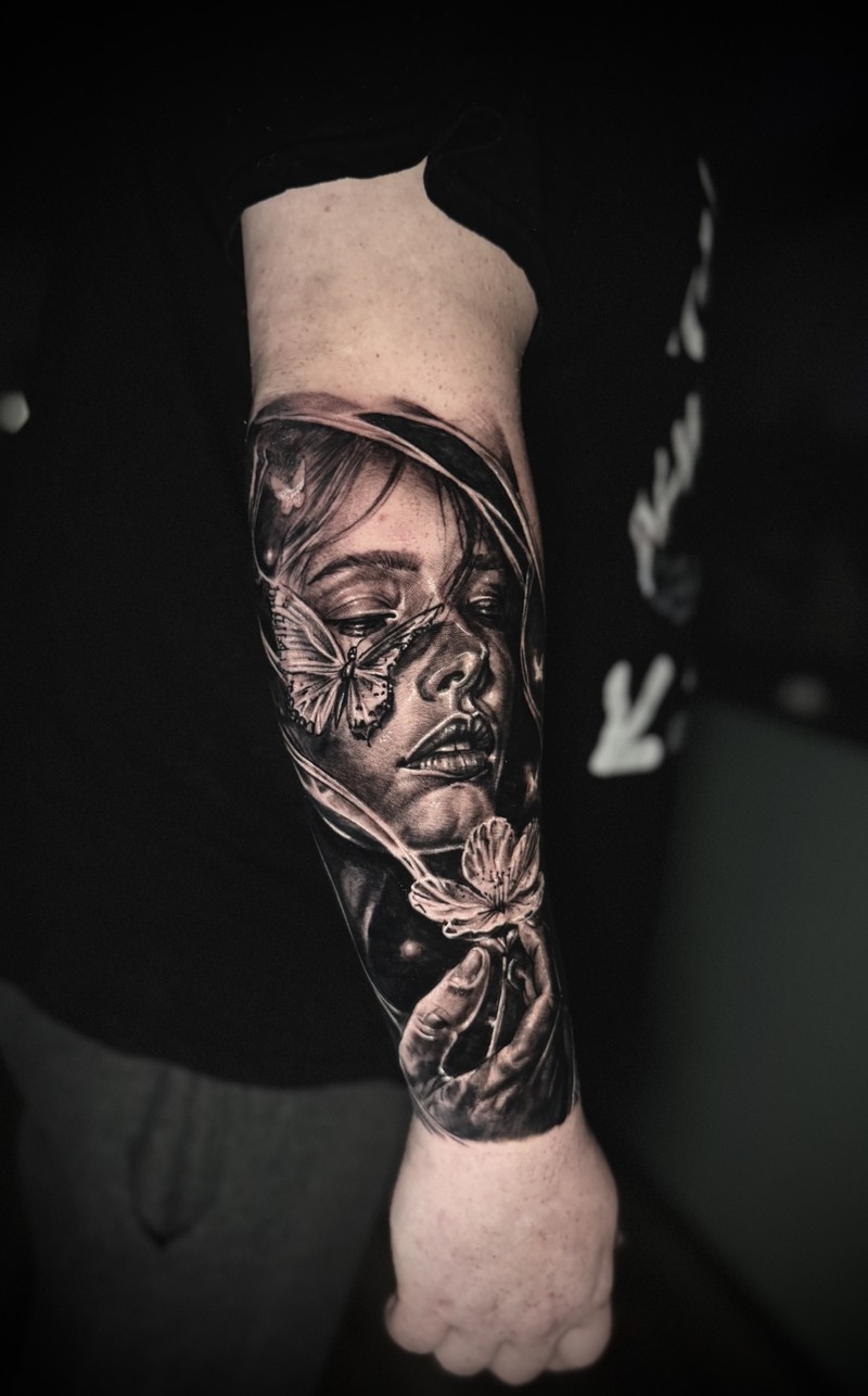 Black and grey female portrait with a butterfly, a flower and a modeled hand.